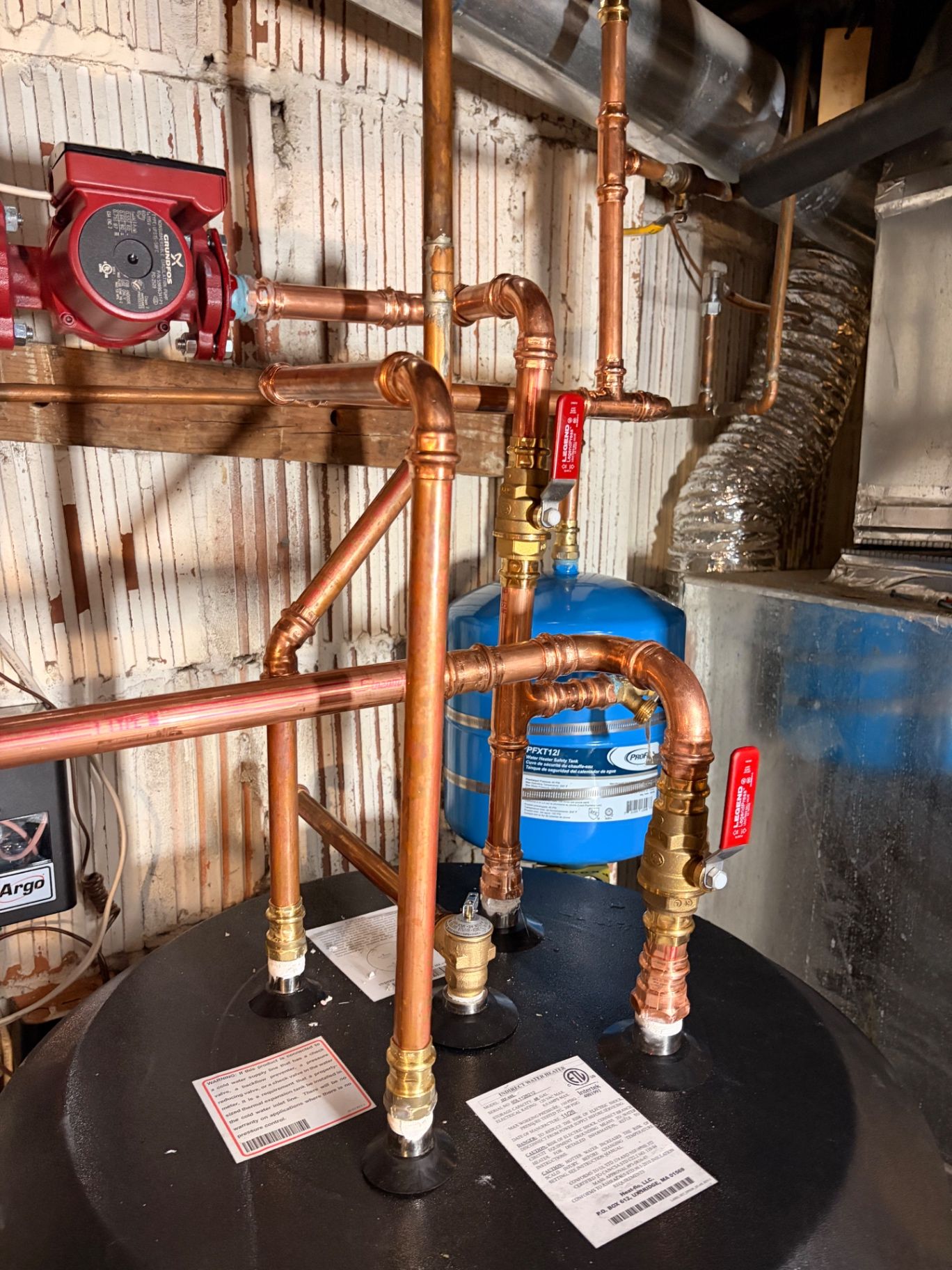 Water heater with a blue expansion tank and copper piping in a mechanical room