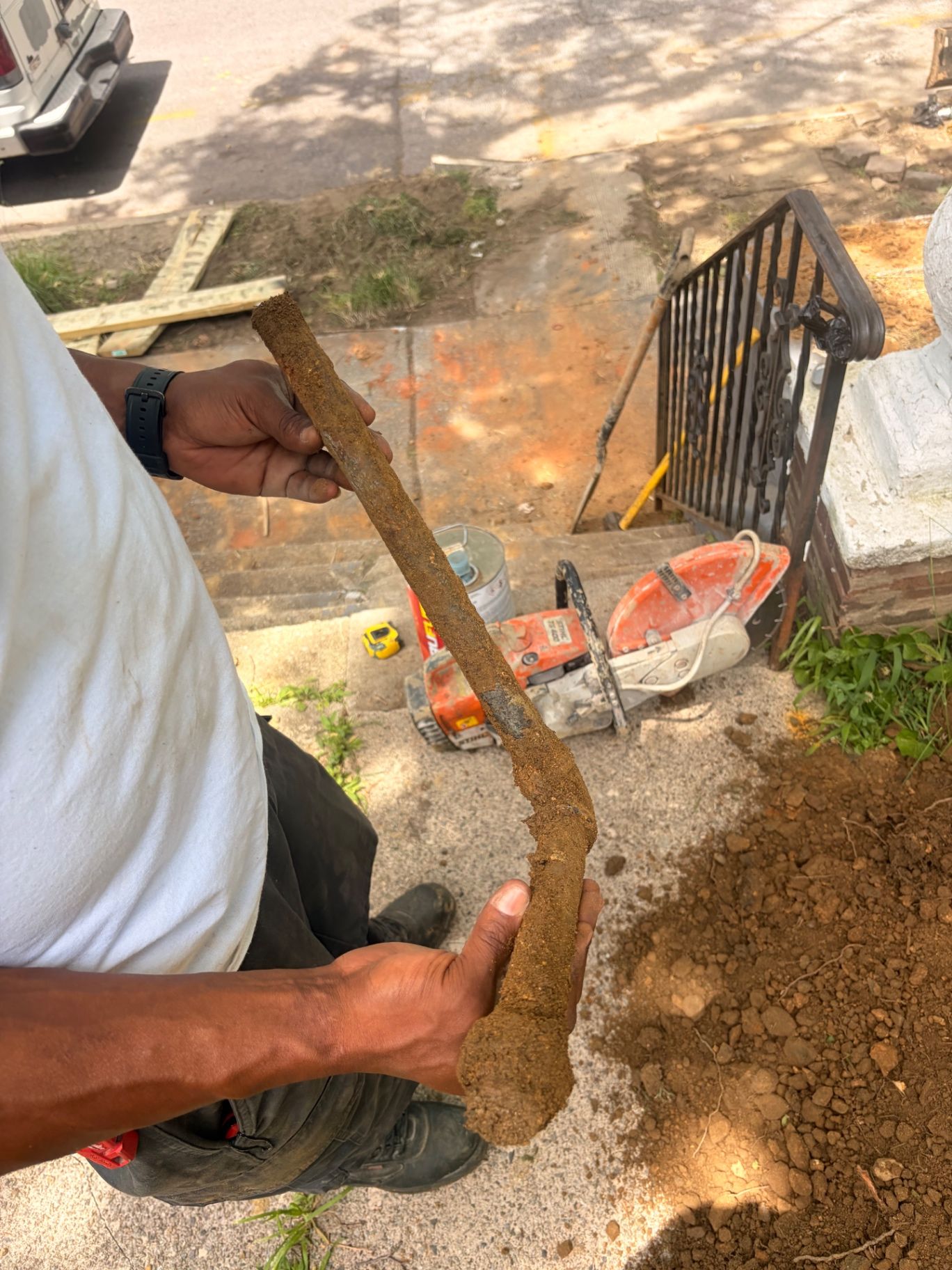 Excavated corroded water line held above an open trench