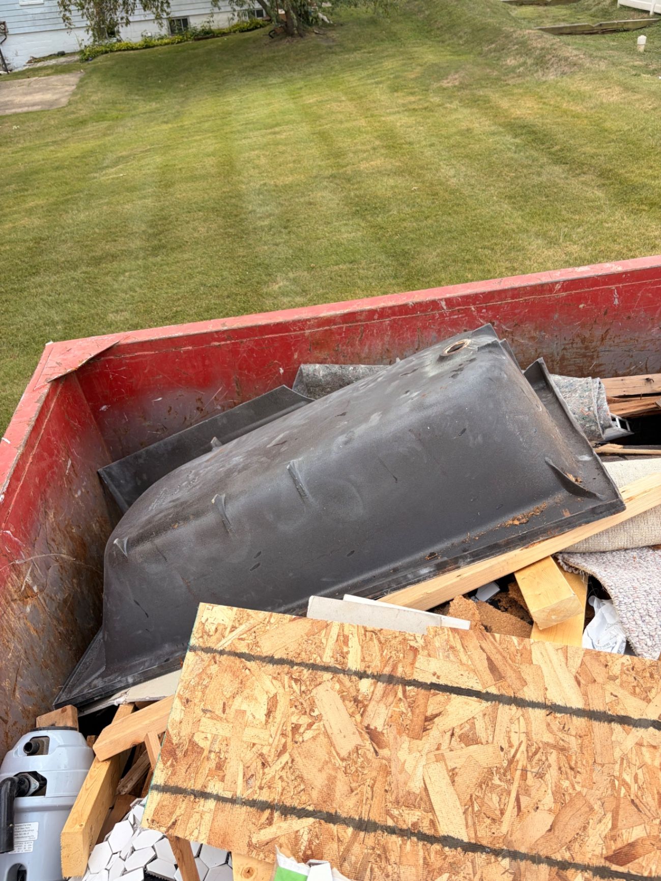 Removed old bathtub in a construction debris container outside a property