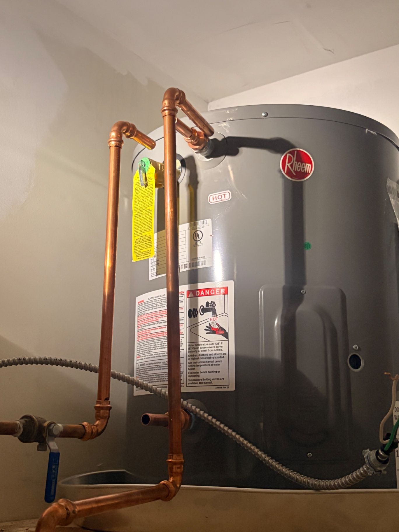 Rheem electric water heater with new copper connections installed in a utility space