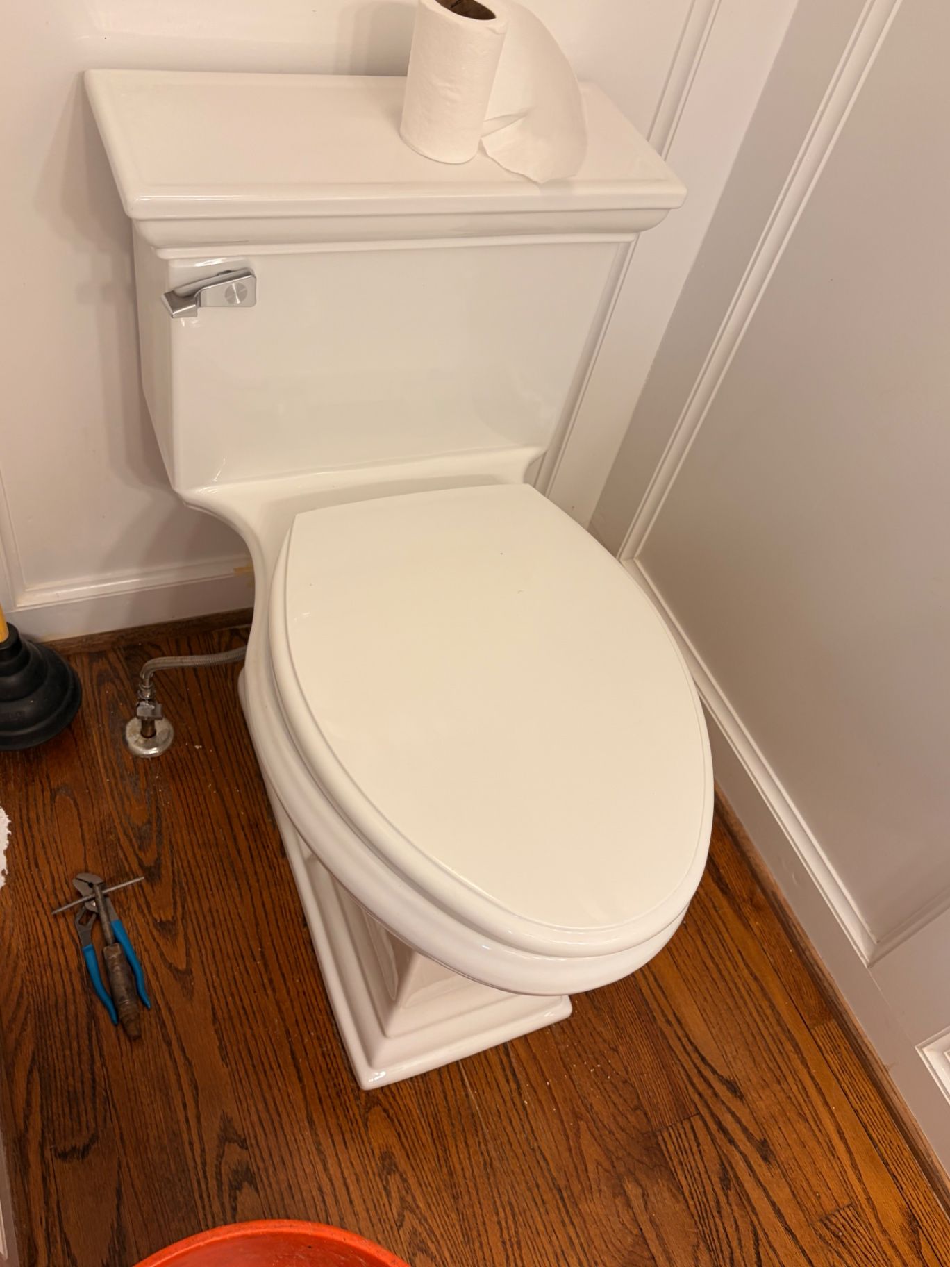 White toilet installed in a bathroom with plumbing tools nearby